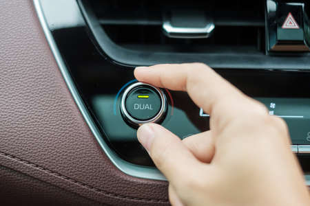 Woman hand adjusting temperature the air flowing during driving car on the road, air conditioner...