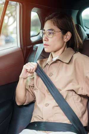 woman driver hand fastening seat belt during sitting inside a car and driving in the road. safety, trip, journey and transport conceptの写真素材