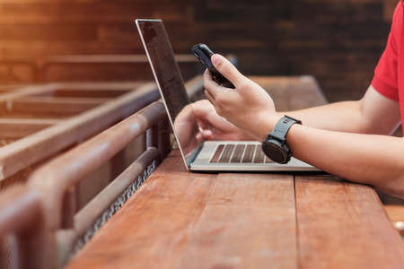 Casual Businessman using smartphone and laptop, freelance man typing keyboard computer notebook in...