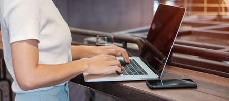 Casual Businesswoman using smartphone and laptop, freelance woman typing keyboard computer notebook in cafe or modern office. technology, digital online and network conceptの写真素材
