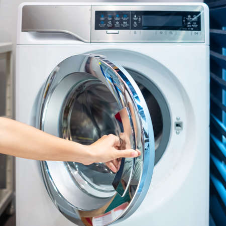 Housewife Woman hand holding clothes inside Washing Machine in laundry roomの写真素材