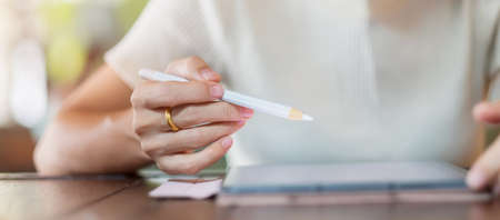 woman using tablet for sms messages, hand holding pencil typing touchscreen mobile phone in cafe or modern office. lifestyle, technology, Social media and network conceptの写真素材