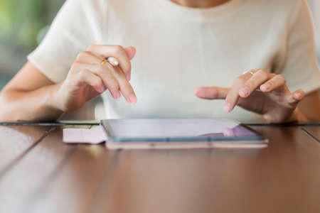 woman using tablet for sms messages, hand holding pencil typing touchscreen mobile phone in cafe or...