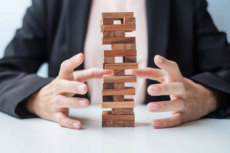 Businesswoman hand cover wooden block on the tower. Business planning, Risk Management, Solution, insurance and strategy Conceptsの写真素材