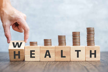 hand flip wooden block WEALTH to HEALTH with coins stack. Investment, Healthcare, Insurance and Work...