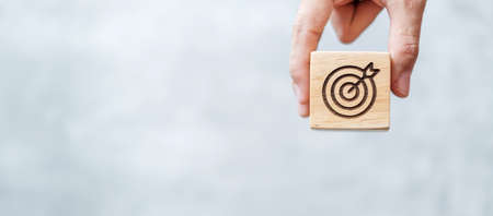 hand hold dartboard block with business goal, strategy, target, mission, action, objective, aim and success conceptの写真素材