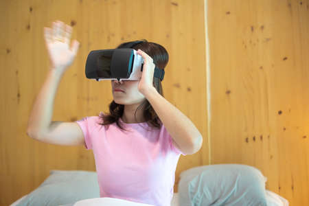 Young woman using virtual reality headset in bed. VR, Future digital technology, game, movies...