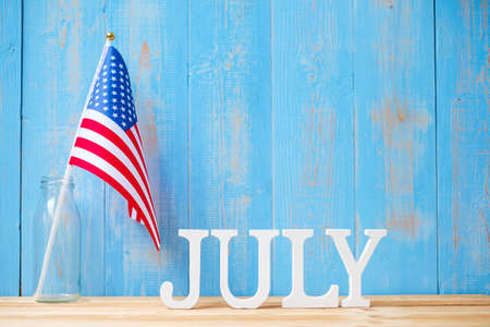 July text and United States of America flag on wooden table background. USA holiday of Independence and celebration conceptsの写真素材