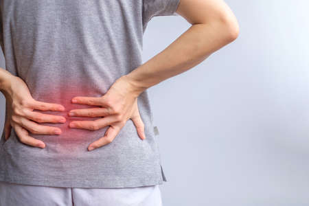 adult female with muscle pain on gray background. Elderly woman having back body ache due to...