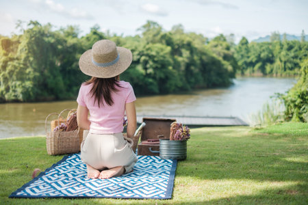 Happy Woman with hat in picnic time in the park near river, Summer, spring and vacation conceptの写真素材