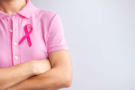 Pink October Breast Cancer Awareness month, woman hand hold pink Ribbon and wear shirt for support people life and illness. National cancer survivors month, Mother and World cancer day conceptの写真素材