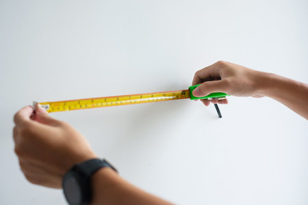 Man hand using tape measure for measuring with wall backgrounds at home. DIY, Interior design,...