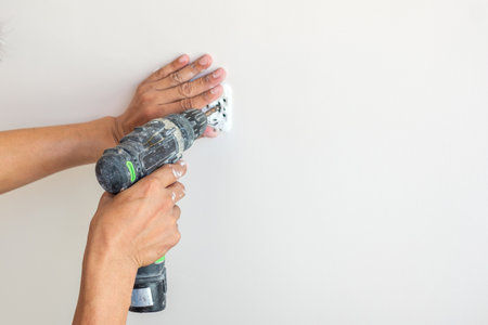 Electrician hand with cordless screwdriver installing Wire cables for socket plug to a concrete. Renovation, Repair, service and development of home and apartment conceptsの写真素材