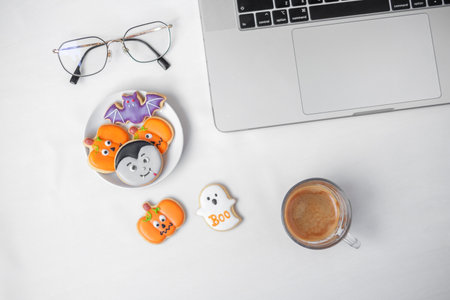 Halloween Cookies,  hot coffee and computer laptop on white background. Happy Halloween, online...