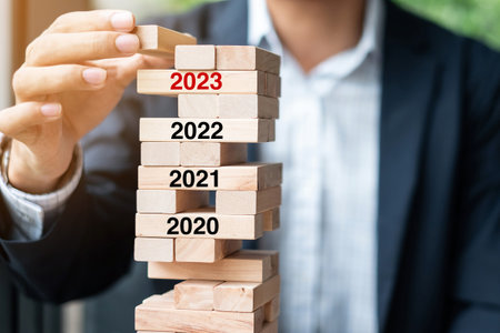 2023 year Goals, Business planning, Risk Management, Solution and strategy Concepts. Businessman hand placing or pulling wooden block on the towerの写真素材