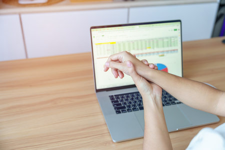 Woman having wrist pain when using laptop computer and mouse during working long time on workplace....