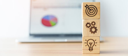 dartboard above Gear and Lightbulb icon block against laptop with business data graph on table. business planning process, goal, strategy, target, mission, action, objective, teamwork and idea conceptの写真素材
