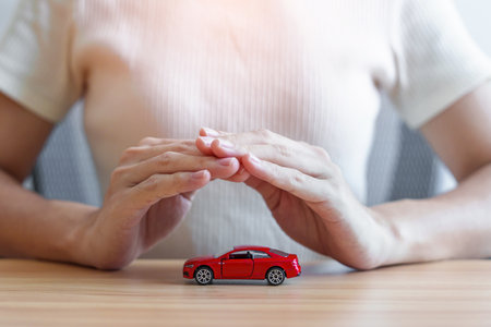 hand cover or protection red car toy on table. Car insurance, warranty, repair, Financial, maintenance  and rental conceptの写真素材