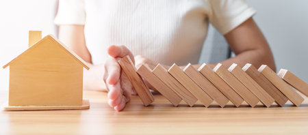 woman hand stop falling wood blocks and protect house model. Crisis, fall Business, Risk, Economic recession, Developer, Real Estate and Property conceptの写真素材