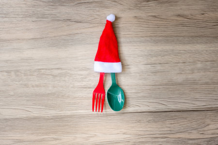 Merry Christmas with miniature Santa Claus, fork and spoon on wood table background. Xmas, party and happy New Year conceptの写真素材