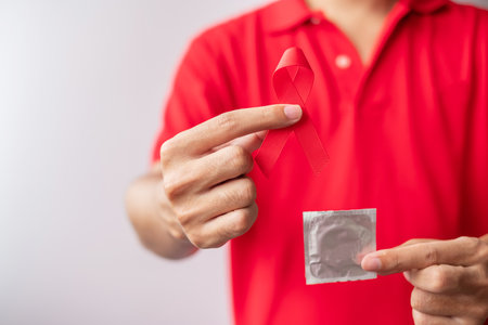 December World Aids Day with red ribbon and condom, acquired immune deficiency syndrome, prevention,...