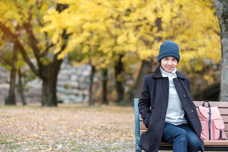 Happy woman enjoy at the park outdoor in Autumn season, Asian traveler in coat and hat against...