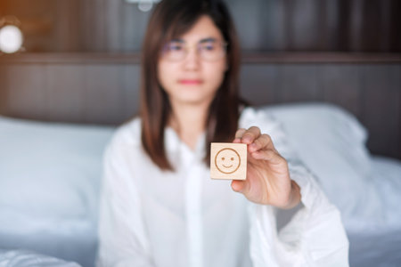 Happy Woman holding smile emotion face block. Customer choose Emoticon for user reviews. Service rating, mental health, positive thinking, satisfaction, evaluation and feedback conceptの写真素材