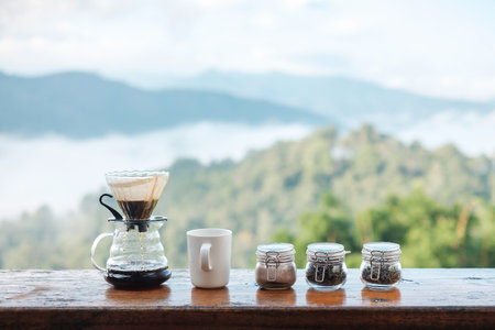 arabica coffee brewing by Vintage coffee drip equipment set on wooden table in the morning with mountain and nature backgroundの写真素材