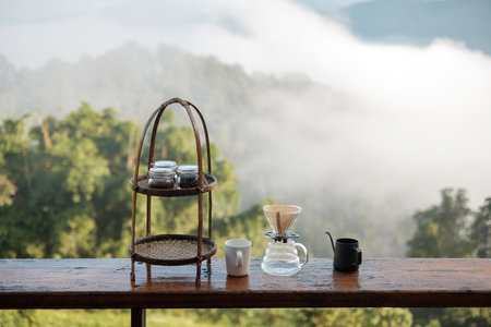 arabica coffee brewing by Vintage coffee drip equipment set on wooden table in the morning with mountain and nature backgroundの写真素材