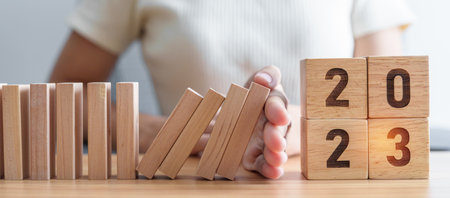 Hand stop falling blocks with 2023 year. Risk Management, recession, business financial, Resolution,...