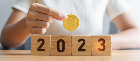 hand holding golden Bitcoin or BTC cryptocurrency over 2023 Year blocks. Crypto trading, is Digital Money, blockchain and New Year conceptsの写真素材