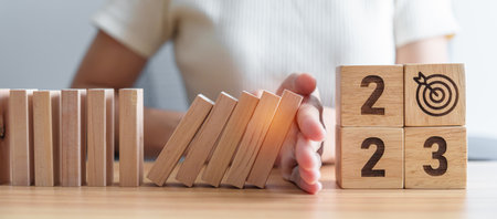 Hand stop falling blocks with 2023 year. Risk Management, recession, business financial, Resolution,...