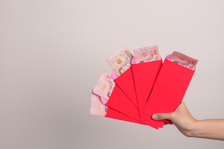 Woman holding Chinese red envelope with Thai baht money gift for happy Lunar New Year holidayの写真素材