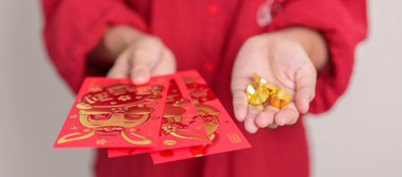 Woman holding Chinese red envelope with gold bullion, money gift for happy Lunar New Year holiday. Chinese sentence means happiness, healthy, Lucky and Wealthyの写真素材