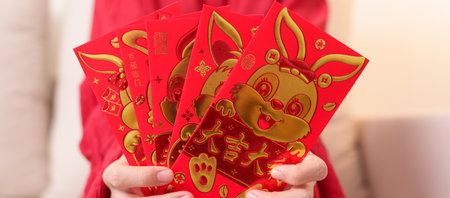 woman holding Chinese red envelope with golden rabbit and blessing word, money gift for happy Lunar...