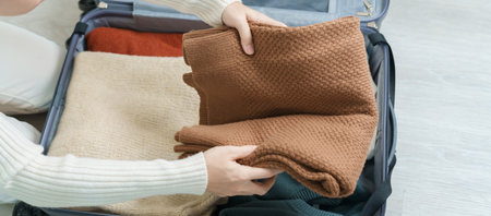 Woman hand packing her winter clothes in luggage. Time to travel, trip, Relax, spring or autumn or...