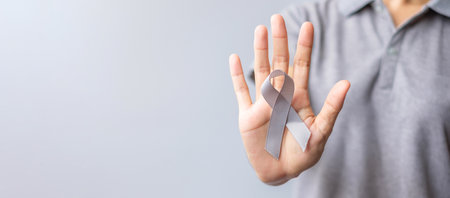 Brain Cancer Awareness month, woman hand holding grey color Ribbon for supporting people life. Healthcare and World cancer day conceptの写真素材
