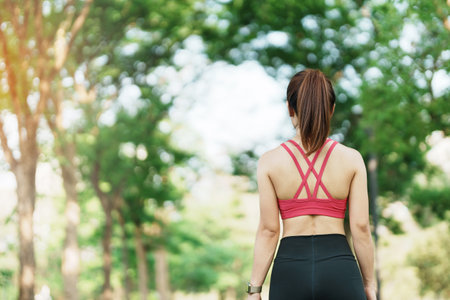 Young adult female in pink sportswear stretching muscle in the park outdoor, sport woman warm up ready for running and jogging in morning. wellness, fitness, exercise and work life balance conceptsの写真素材