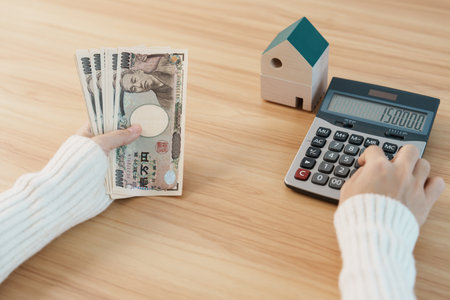 Woman counting Japanese Yen banknote with House model. Real Estate, Home, Mortgage, Japan cash, Tax, Recession Economy, Inflation, Investment, finance and savings conceptsの写真素材