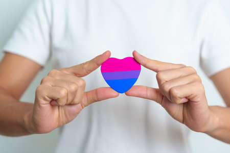 Bisexuality Celebrate Day and LGBT pride month,  LGBTQ+ or LGBTQIA+ concept. Hand holding purple, pink and blue heart shape for Lesbian, Gay, Bisexual, Transgender, Queer and Pansexual communityの写真素材