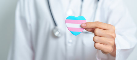 Transgender Day and LGBT pride month,  LGBTQ+ or LGBTQIA+ concept. Doctor holding blue, pink and white heart shape for Lesbian, Gay, Bisexual, Transgender, Queer and Pansexual communityの写真素材