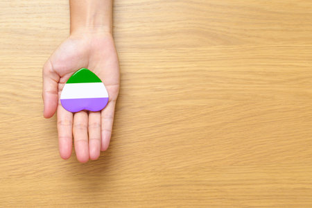 Queer Pride Day and LGBT pride month concept. hand holding purple, white and green heart shape for Lesbian, Gay, Bisexual, Transgender, genderqueer and Pansexual communityの写真素材