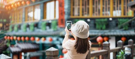 woman traveler visiting in Taiwan, Tourist taking photo and sightseeing in Jiufen Old Street village with Tea House background. landmark and popular attractions near Taipei city. Travel conceptの素材 [FY310204020478]