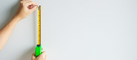 Man hand using tape measure for measuring with wall backgrounds at home. DIY, Interior design, repairing and improvement home or apartment conceptsの写真素材