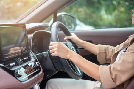 woman driver driving a car on the road, hand controlling steering wheel in electric modern automobile. Journey, trip and safety Transportation conceptsの写真素材