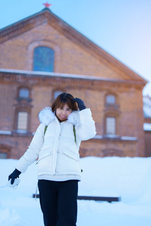 Woman tourist Visiting in Sapporo, Traveler in Sweater looking Sapporo Beer Museum with Snow in winter season. landmark and popular for attractions in Hokkaido, Japan. Travel and Vacation conceptの写真素材