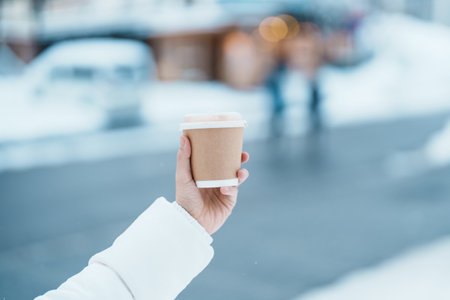 woman tourist holding hot Coffee or Tea paper cup with snow in winter season during travel in...