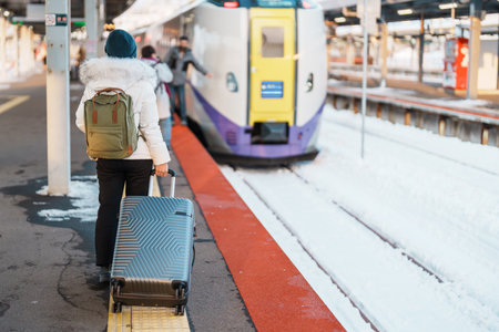 Woman tourist with bag in Train Station platform with Snow in winter. Hakodate, Hokkaido, Japan.Travel and Vacation conceptの写真素材