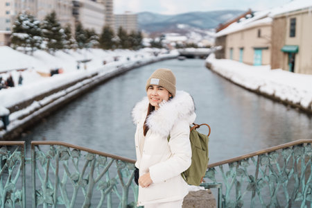 Woman tourist Visiting in Otaru, happy Traveler in Sweater sightseeing Otaru canal with Snow in winter season. landmark and popular for attractions in Hokkaido, Japan. Travel and Vacation conceptの写真素材