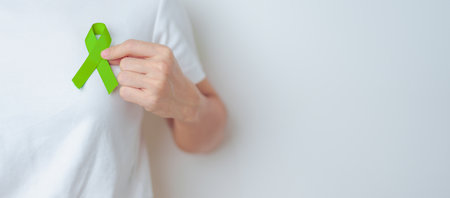 Woman holding green Ribbon for world Lymphoma Awareness September month, world Mental Health Day, Liver, Gallbladders, bile duct, cervical, kidney Cancer. Healthcare and world cancer day conceptの写真素材
